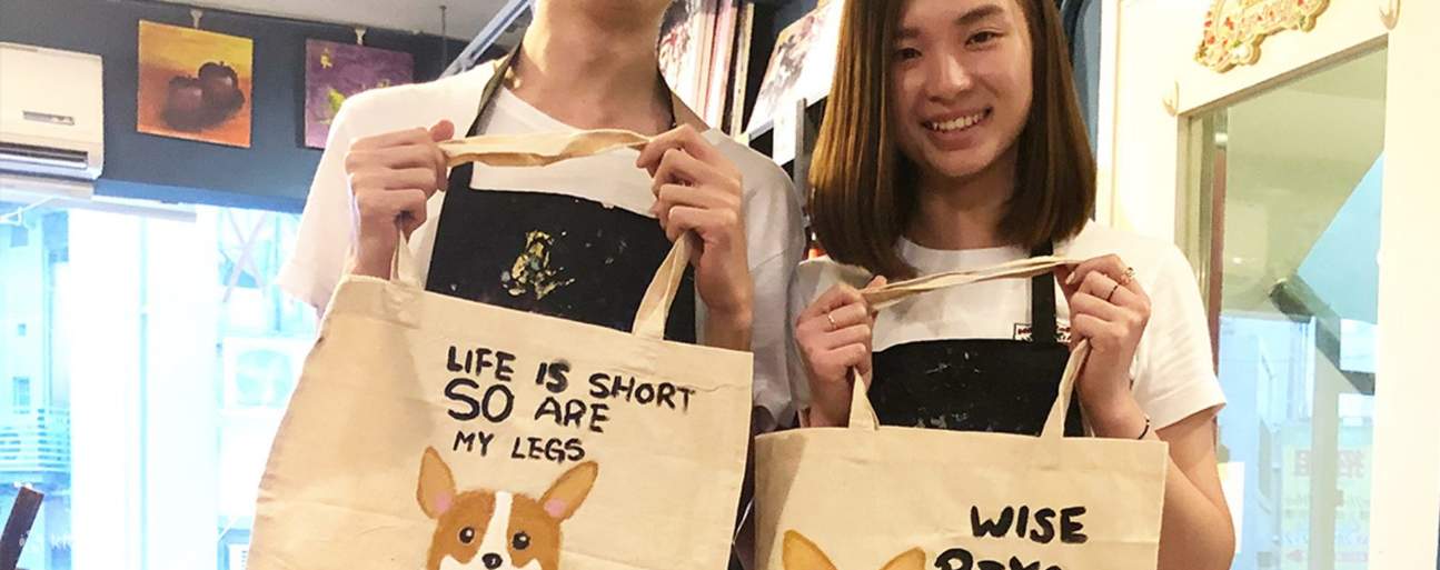 Два человека с раскрашенными сумками-шопперами в Aura Art Causeway Bay